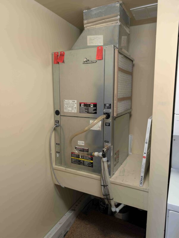 Front view of a brand new ClimateMaster residential heat pump system, featuring an attached air filter and properly secured water lines.