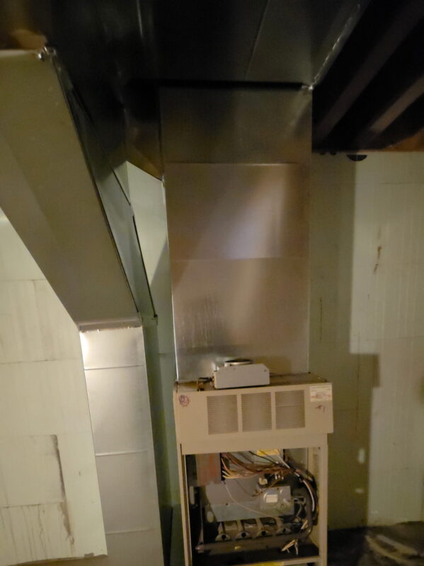 A newly installed furnace system connected to custom ductwork in a home basement.