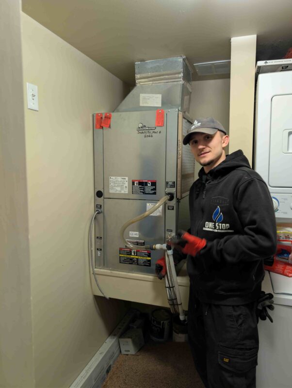A professional HVAC technician from One Stop HVAC demonstrating the newly installed ClimateMaster heat pump equipment and its setup.